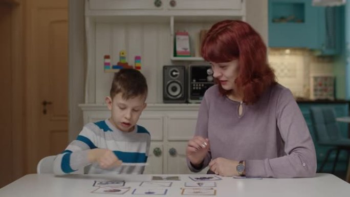 自闭症治疗师与自闭症儿童一起练习阅读技能。自闭症男生在家和妈妈一起学习。自闭症儿童将单词与图片匹配。