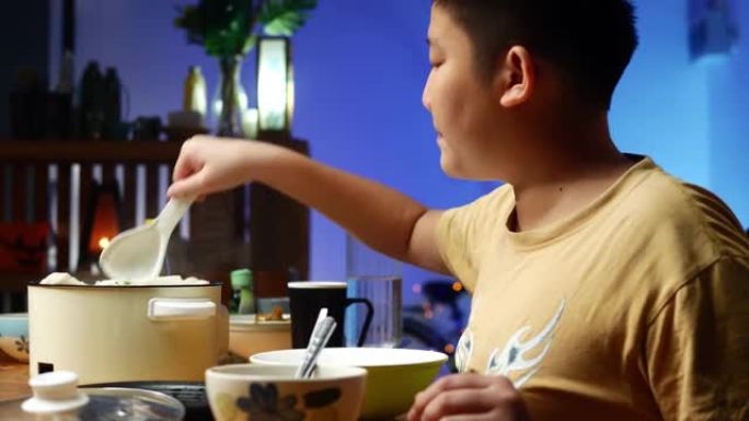 快乐的亚洲男孩和他的妹妹在家里一起用寿喜烧或sha锅做饭，生活方式概念。