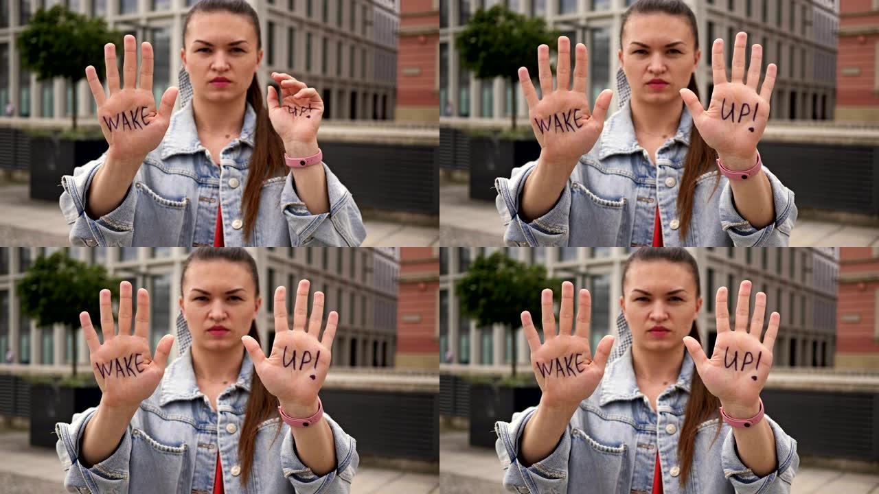 单一的抗议者。一位严肃的年轻女子拿出她的手掌，上面写着“醒醒”。她呼吁采取行动