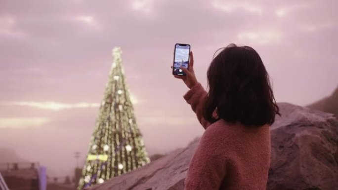 女人在观景角巴纳山用手机给圣诞树拍照。