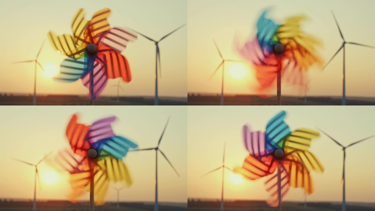 风车旋转彩色塑料，风车吹着风力涡轮机的风，风公园夕阳夏日。太阳的明亮圆盘下降到地平线之外。镜头光斑。
