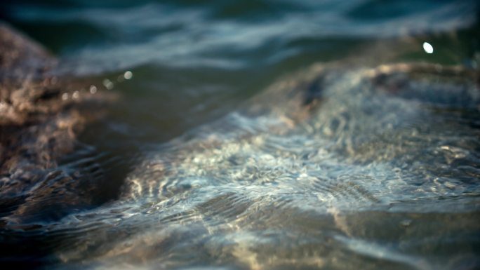 清澈湖水波浪拍打在石头上