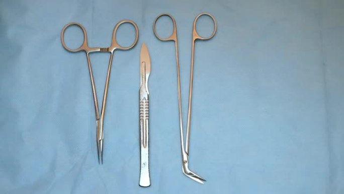 蓝色桌子上的多个手术器械。外科医生从桌子上拿走手术工具。