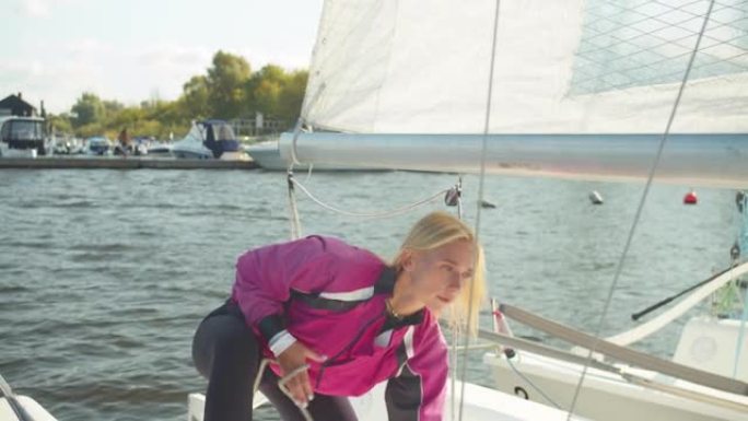 一位美丽的年轻女子在阳光明媚的夏日为帆船帆船赛准备游艇的索具。拉绳扬帆