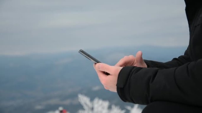 男手拿手机在雪山背景上