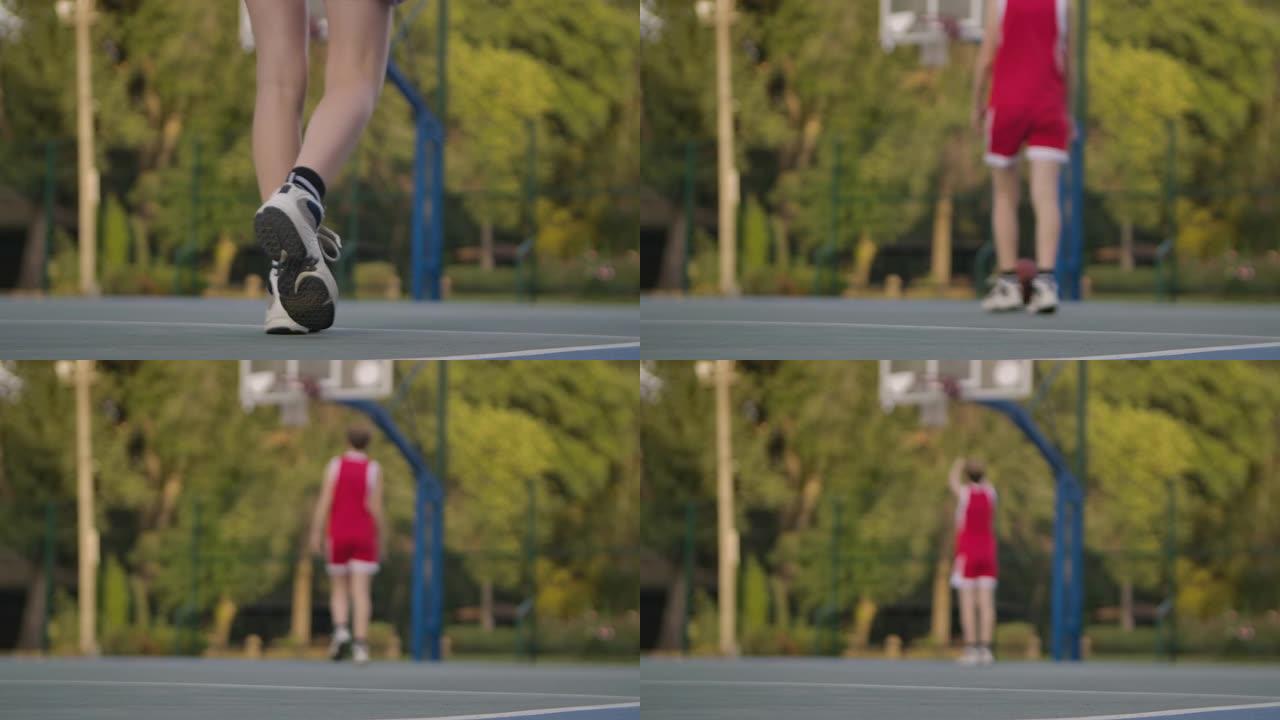 篮球位于运动场上。无法识别的球员捡起球并运球到篮筐。独自练习街球。背景模糊。腿靠近。慢动作