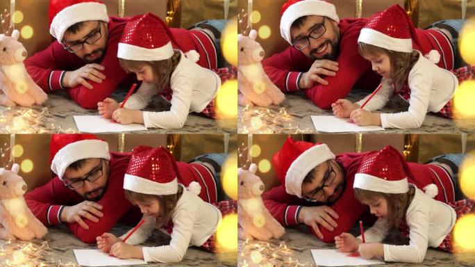 年轻的父亲和小女孩的特写，戴着红色的圣诞老人帽子，给圣诞老人写信的背景是盒子的圣诞节。幸福的家庭庆祝