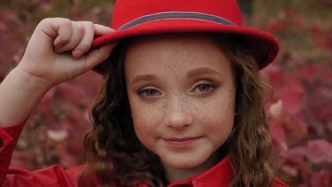 秋天，一个戴着红帽子的雀斑的红发小女孩的肖像。