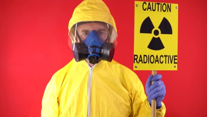 一名男子穿着防护化学服，戴着防护面具，海报上写着 “小心辐射”。红色背景上的辐射危害概念。隔离，工作