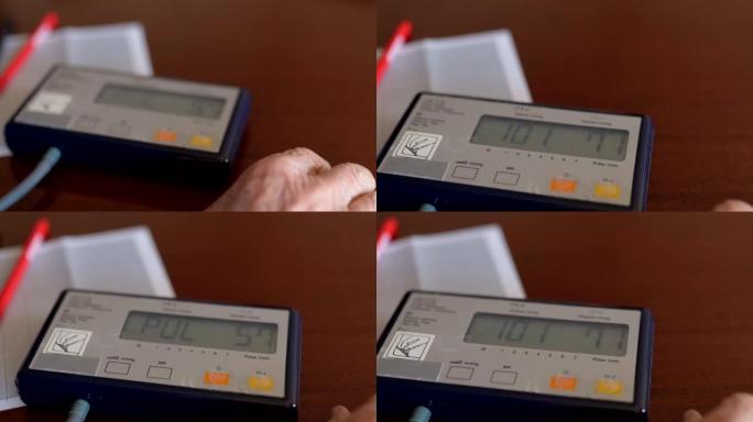 在餐桌上的老式自动压力装置的特写镜头，老人在家中测量血压和脉搏，以预防心脏病发作或心脏骤停。老人的疾