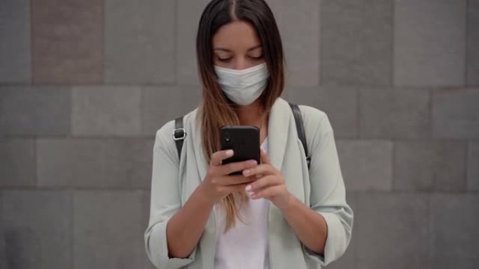 城里的职业女性从口袋里掏出一部智能手机。她为冠状病毒大流行掩饰自己。