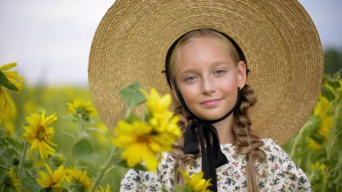 夏天村向日葵田上戴着两根辫子的肖像漂亮女孩。漂亮的乡村女孩，发辫和草帽在黄色向日葵背景上摆姿势。
