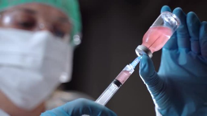 模糊的医学科学研究人员用无菌小瓶的红色溶液填充注射器，生物物理学家准备注射用于测试人。预防冠状病毒感