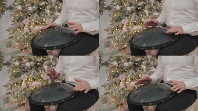 一个男人在房间里玩挂圣诞装饰。音乐家演奏坦克鼓。音乐家演奏手摇。音乐家演奏钢舌鼓