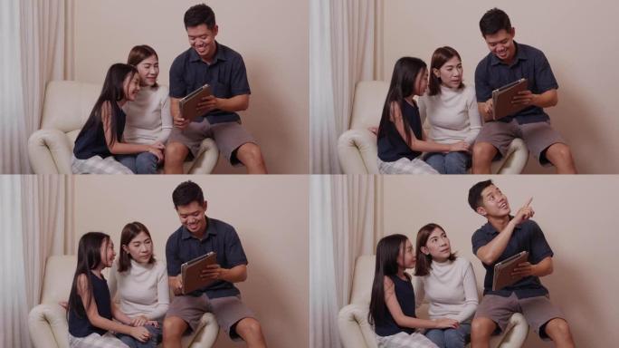 亚洲幸福的父母和漂亮的女儿在家庭时间一起在客厅使用平板电脑上的小工具时很享受。