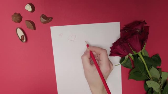一个女人用红色铅笔在白纸上画心。情书。