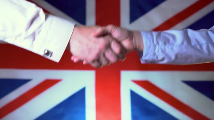 商人和女商人在英国国旗的背景下握手。