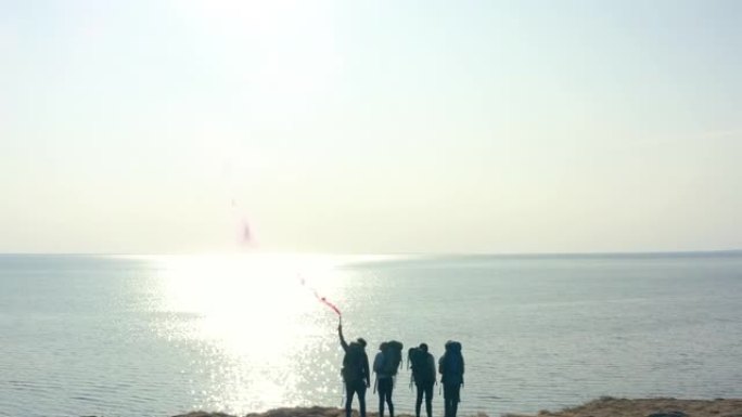 游客用火棍站在海边的沙石顶上