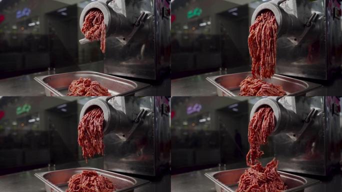 超级慢动作在肉类加工厂用新鲜牛肉在电动绞肉机中制作碎肉。一堆切碎的肉。鲜碎肉绞肉机。用织物研磨机制备