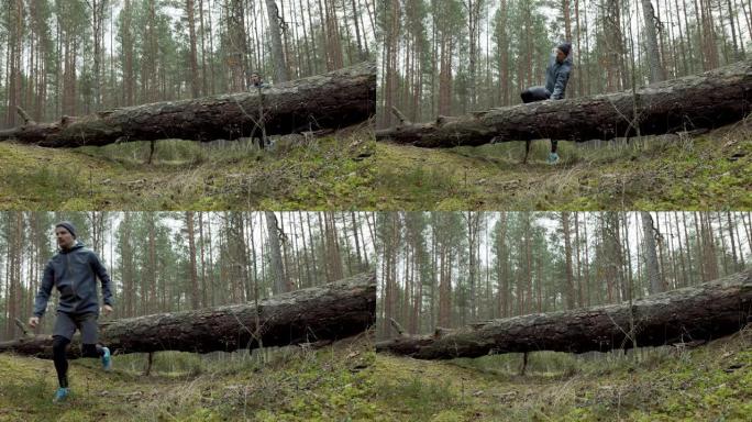 男子在森林小径上奔跑，跳过倒下的老树。慢动作滑块拍摄