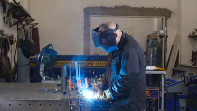 戴着防护面罩和手套的焊工使用焊接机在特殊的工作台上焊接金属零件。半自动气体保护焊。50 fps慢动作