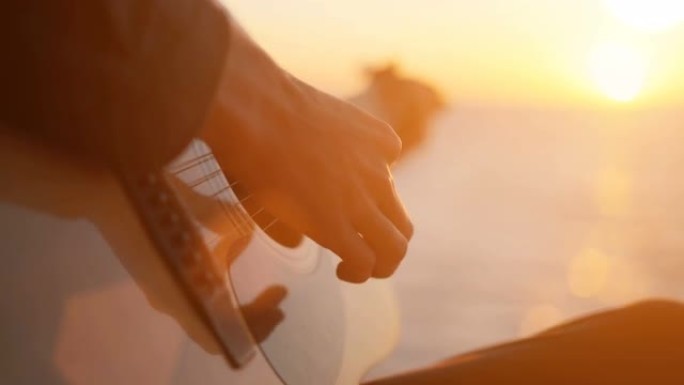 年轻人在海边弹吉他，日落