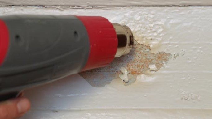木质门窗的简单廉价修复。恢复木匠用热风枪高温和刮铲从涂漆木板表面剥离油漆。家居项目DIY家居室内工艺