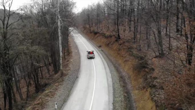 在穿过秋天森林的道路上，从上方看无人机。空中汽车在秋天穿越森林