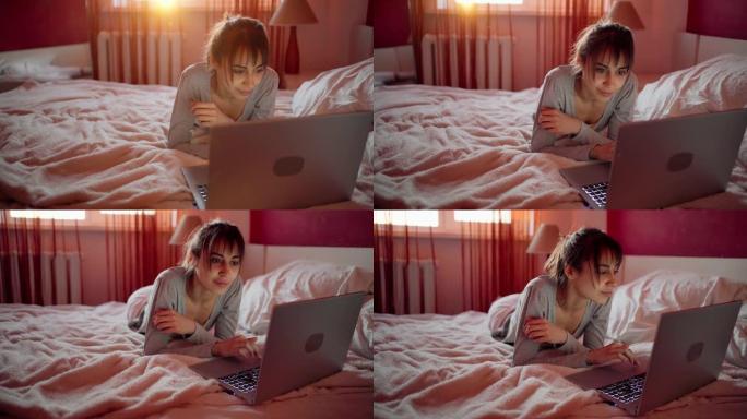 年轻女子躺在家里的床上，看着笔记本电脑，在互联网上浏览