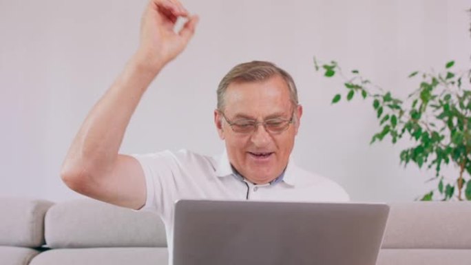 一位老人带着笔记本电脑在阅读好消息时欢呼雀跃