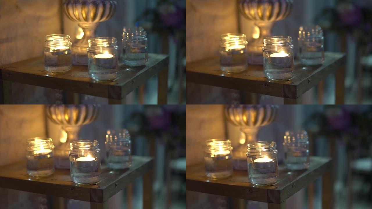晚上，玻璃罐中的蜡烛在装饰木架上燃烧