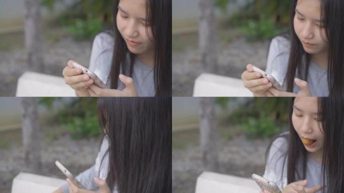 亚洲年轻女子吃饭和玩手机。