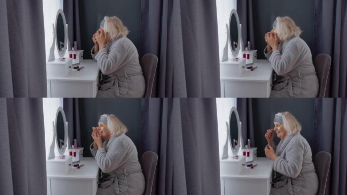 老年老年妇女祖母涂抹抗皱眼罩，在家化妆