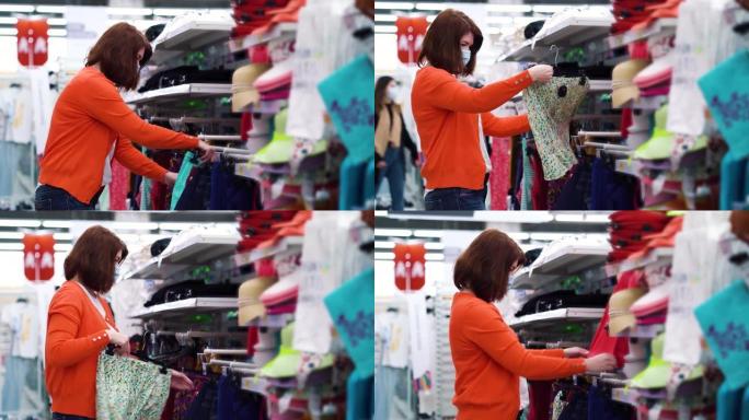 戴医用口罩的女孩在COVID期间在百货商店试穿裙子