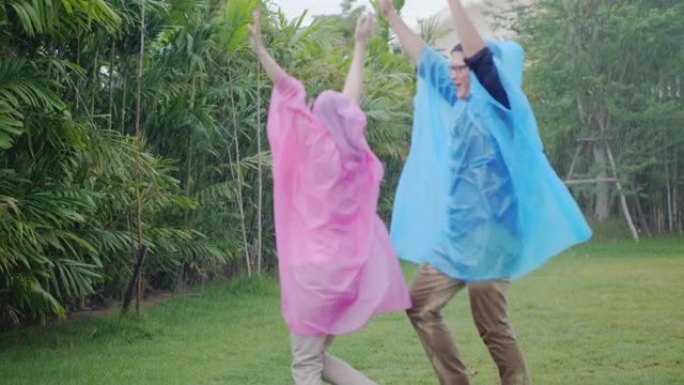 亚洲夫妇穿着五颜六色的雨衣，微笑着在大自然中玩雨很开心