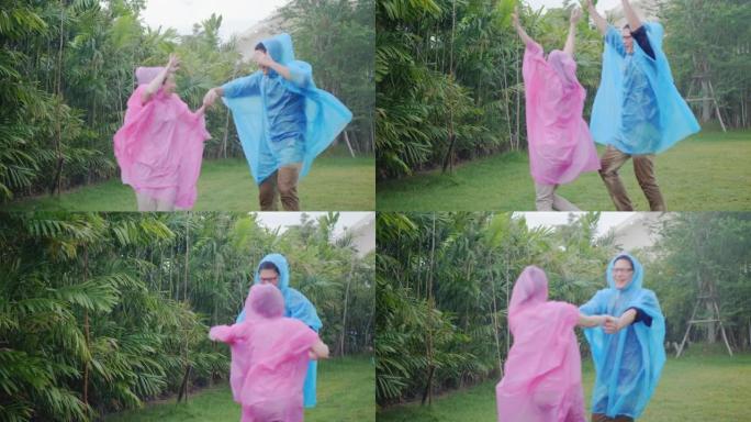 亚洲夫妇穿着五颜六色的雨衣，微笑着在大自然中玩雨很开心