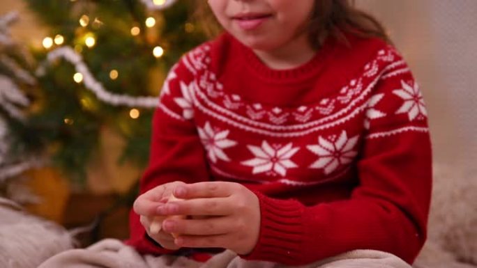 一个戴着圣诞老人帽子的小女孩打开了一个幸运饼干。儿童和成人的传统圣诞乐趣。高质量4k镜头