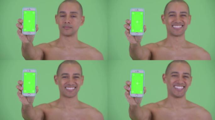 快乐的男人微笑着并显示带有绿色屏幕的电话