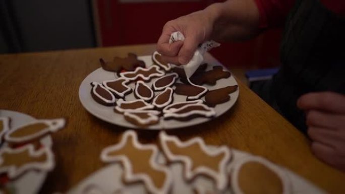 一位面目全非的老妇用糖粉和糕点袋装饰姜饼。圣诞姜饼，自制饼干，家庭传统