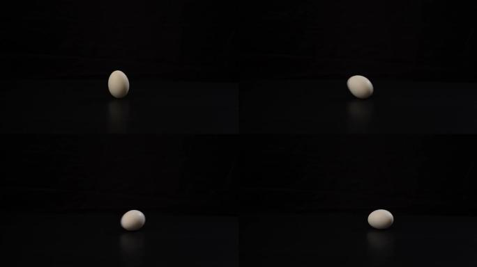 戴上黑色手套会扭曲一个白色的鸡蛋，然后在黑色背景上的深色硬表面上继续旋转。