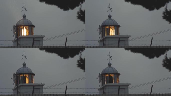 灯塔发出的光束透过雨滴闪耀。海边的恶劣天气