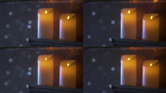 两支白色蜡烛，带有人造灯，在大理石墙的背景下，内部的花环在散焦闪烁。