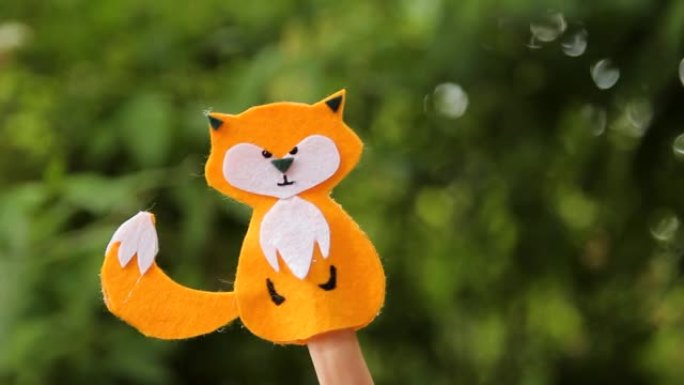 女孩在春天用手指展示她手工制作的狐狸玩具