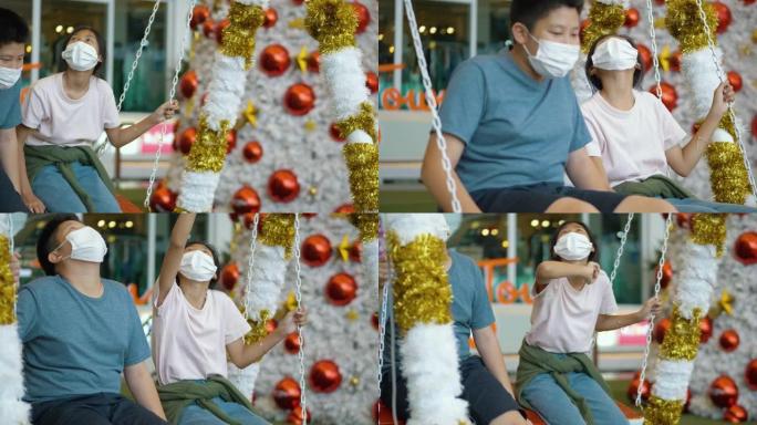 快乐的亚洲儿童戴着口罩，用圣诞树背景拍照或自拍，假期概念。