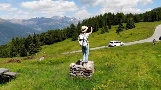 穿着休闲服和帽子的年轻白人女性游客的观点，带着背包在山路上享受时光