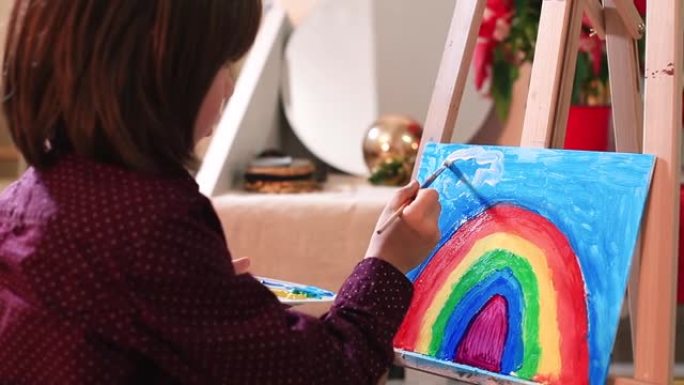 青少年使绘画彩虹坚硬的表面浸入调色板画笔绘制云