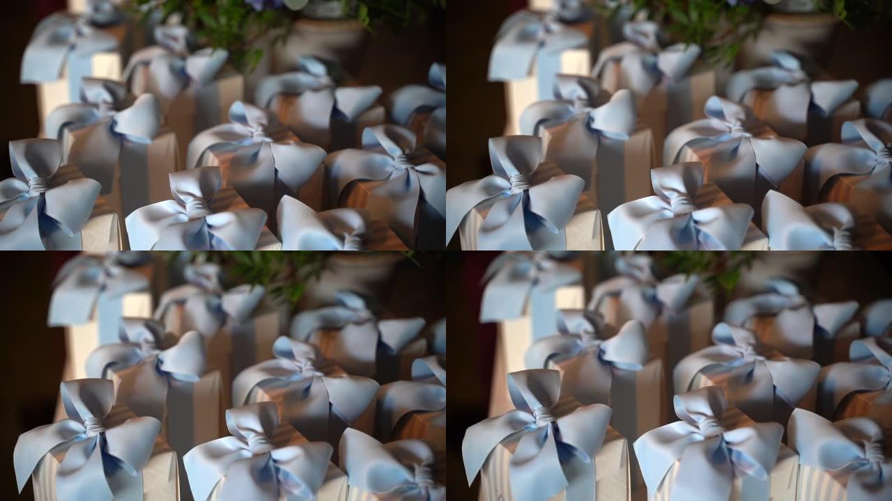 为洗礼派对庆祝活动准备的带蓝丝带的小纸盒特写镜头，宴会桌上有不同五彩纸屑的著名bonbonniere