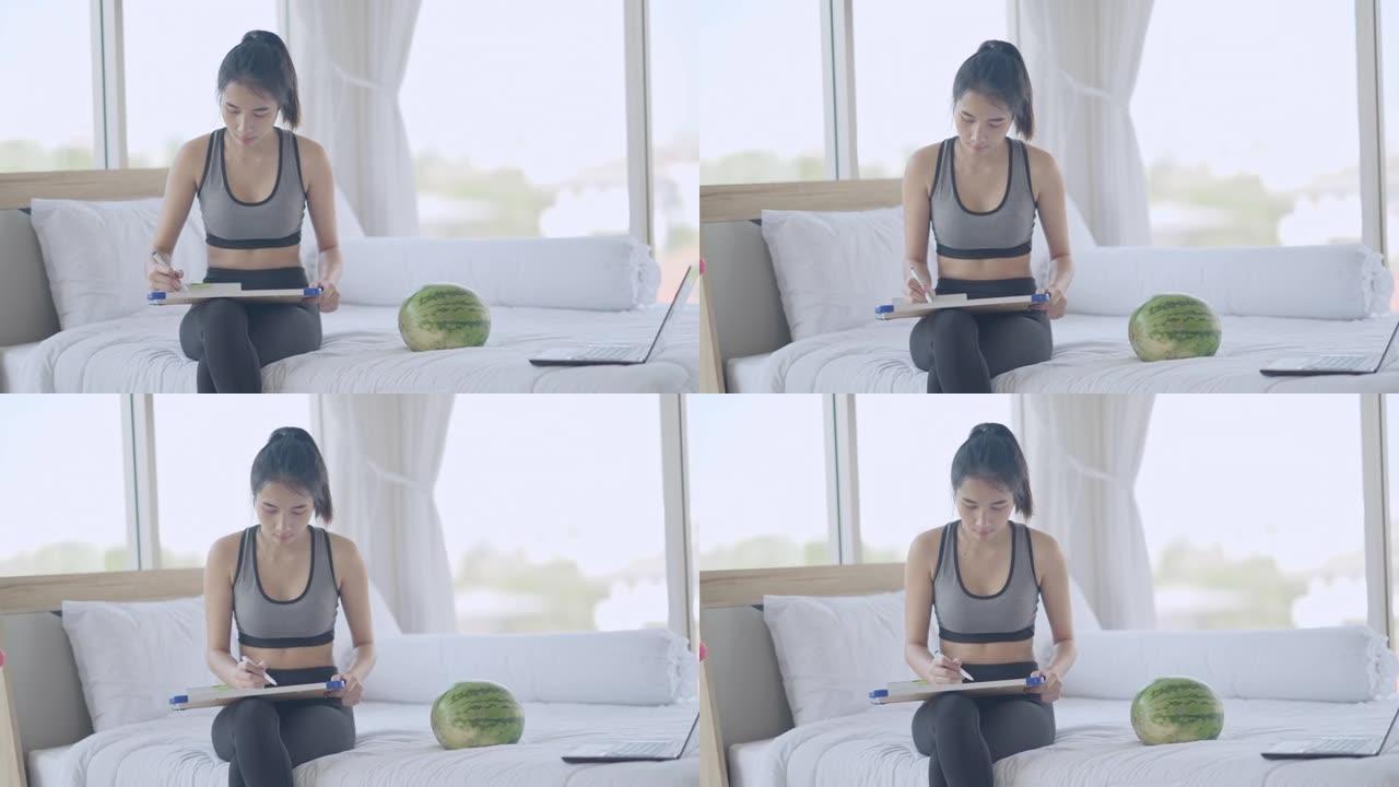 年轻的亚洲妇女在卧室在线教程的帮助下在家用西瓜锻炼