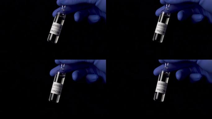 黑色背景上的冠状病毒疫苗安瓿在医生的手中蓝色医用防护手套