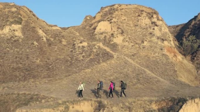 背着背包的四人在沙地山区徒步旅行